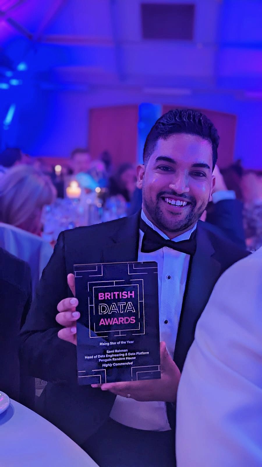 Sami Rahman smiling holding trophy at table